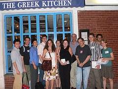 War News Radio poses in front of a Greek restaurant